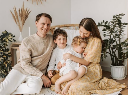 Happy family of four enjoying quality time together in a cozy, plant-filled room.