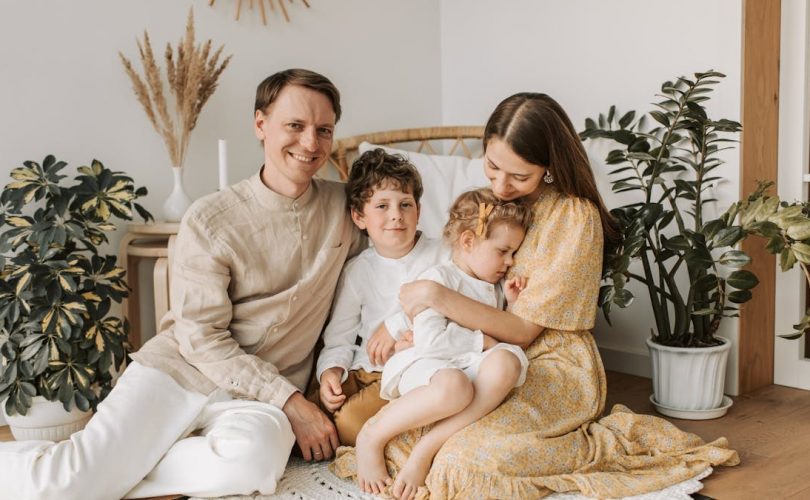 Happy family of four enjoying quality time together in a cozy, plant-filled room.